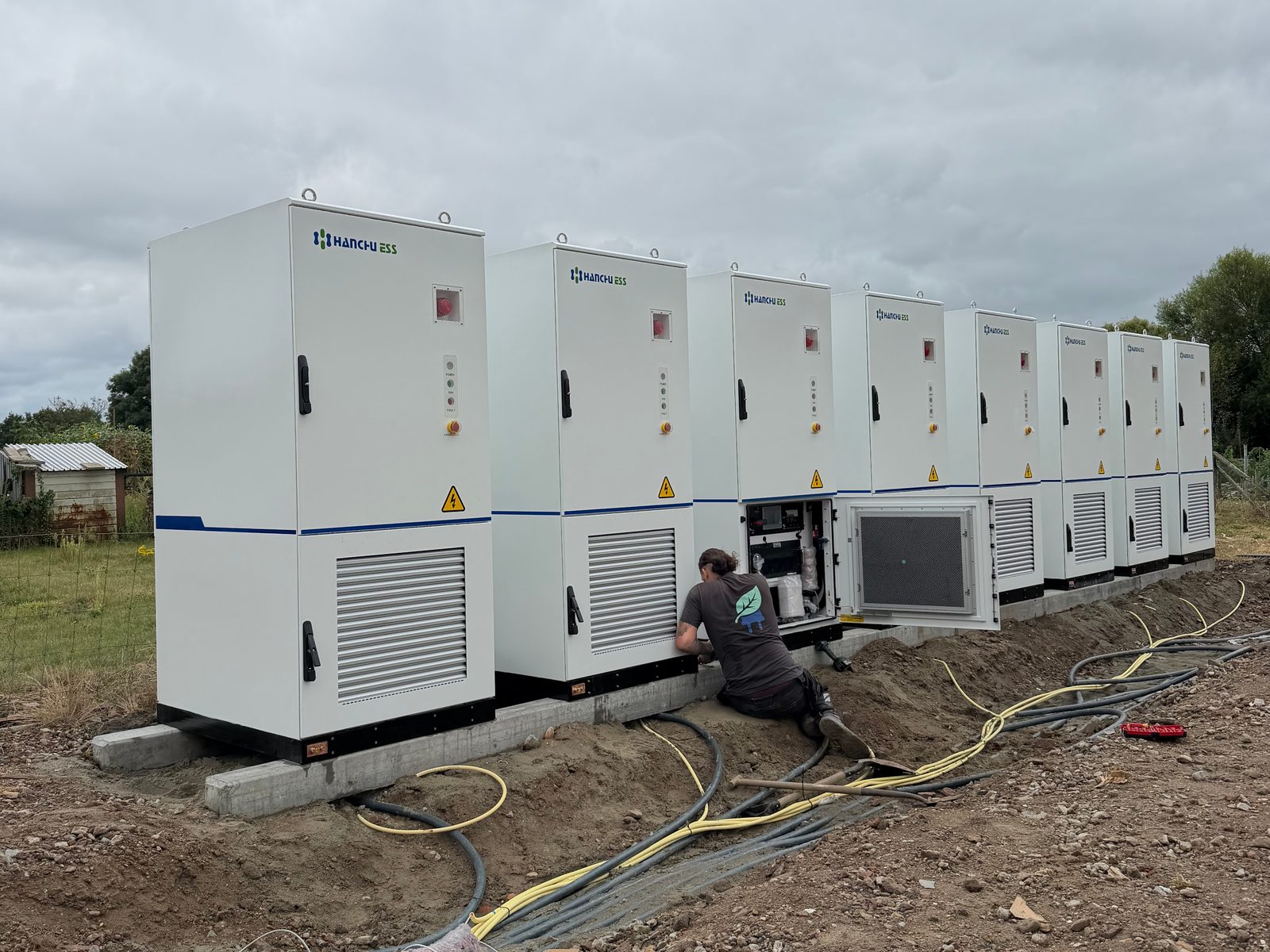 Rij van acht batterijkasten met een monteur van Salm & Helm aan het werk