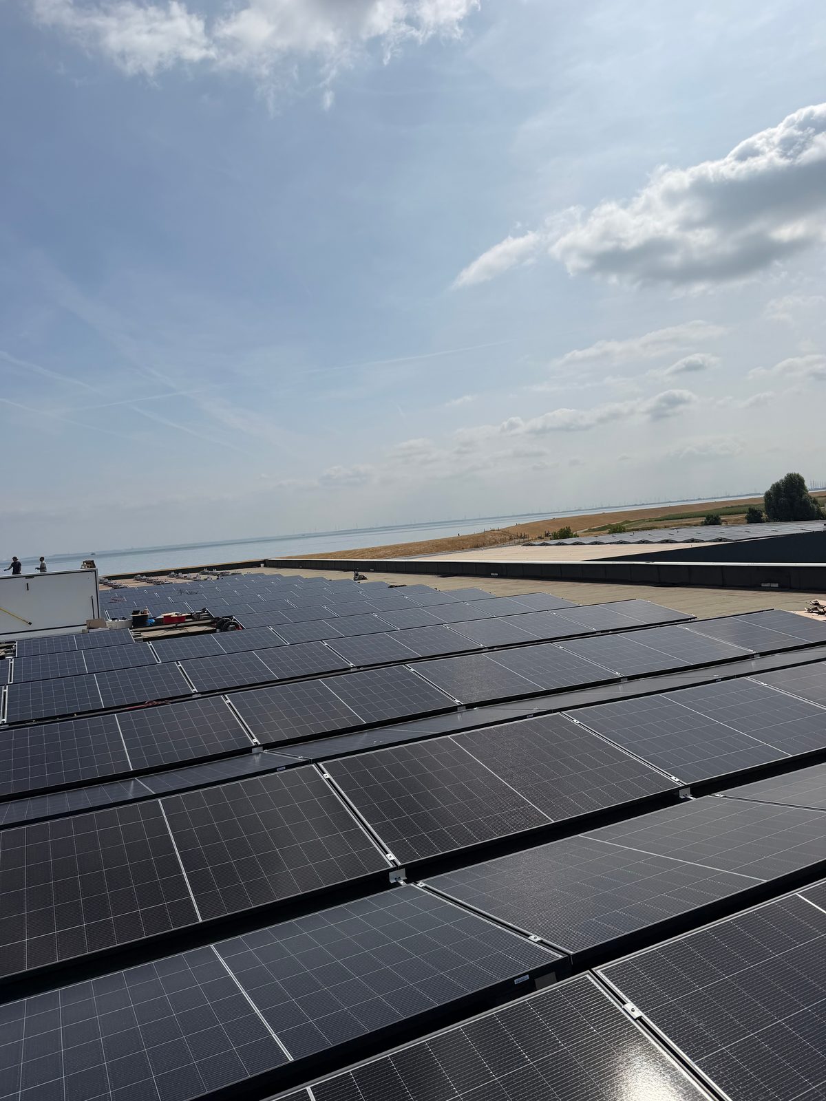 Zonnepanelen op het dak van het bedrijfspand, met zicht op het water