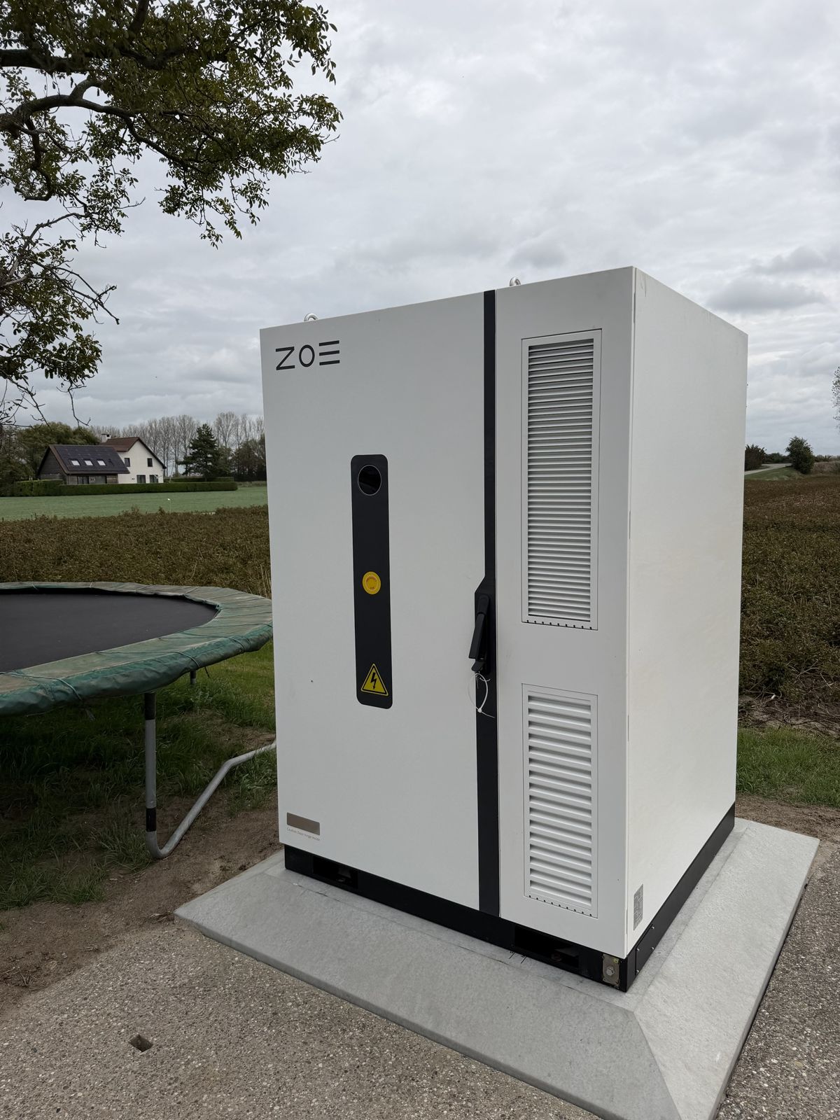 Zakelijke batterijkast op een betonplaat naast het erf