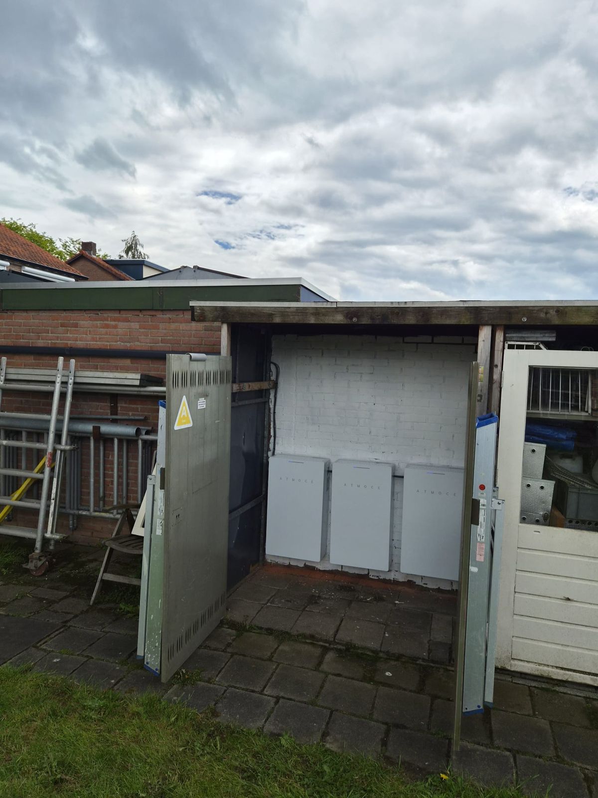 Drie batterijmodules tegen de achterwand van een open tuinschuur