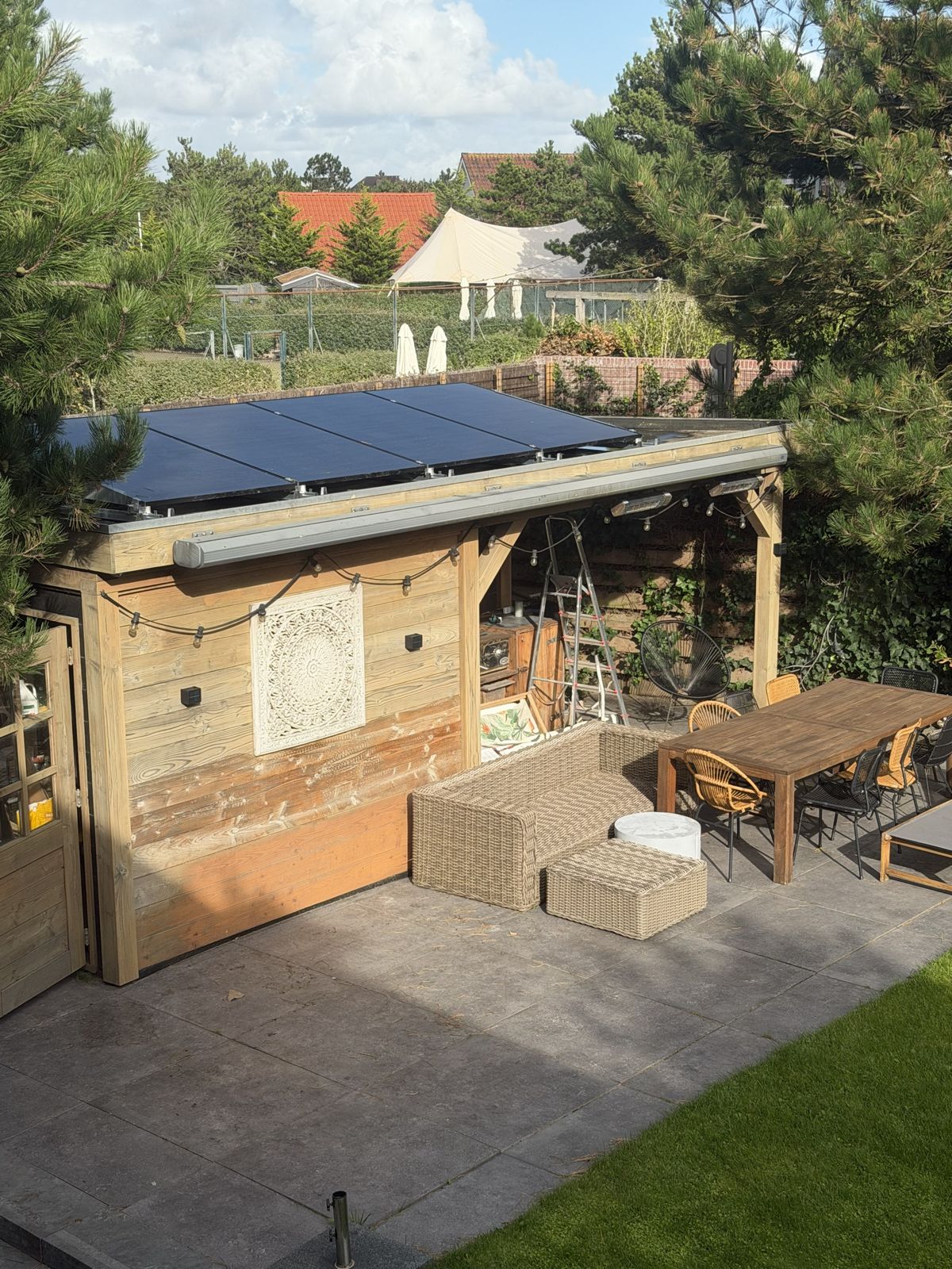 Zonnepanelen op het platte dak van een tuinhuis met overkapping